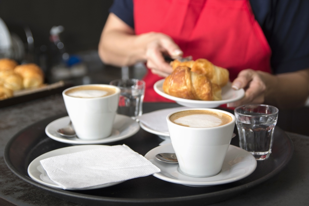 serving-two-coffee-cups-front-waitress-placing-croissant-plate